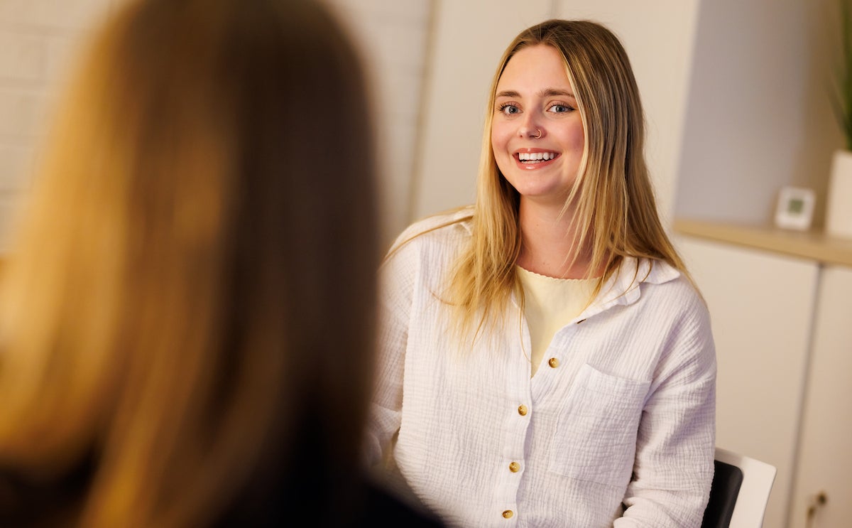 A student smiles as she speaks with an adult.