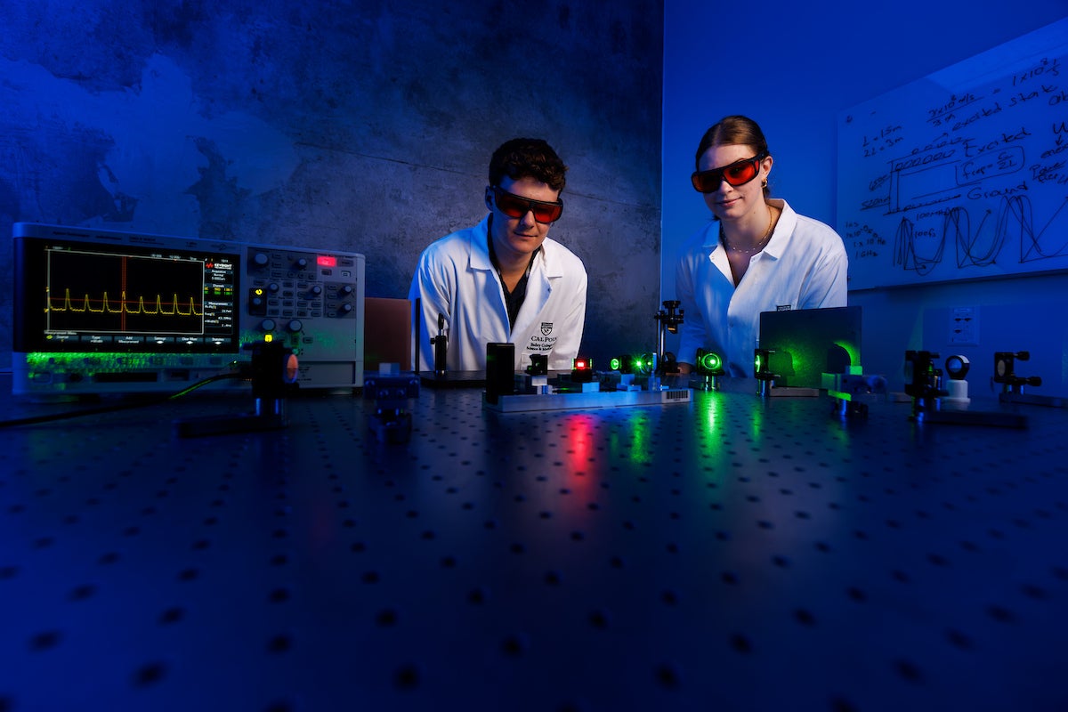 Two students in protective gear observe the laser