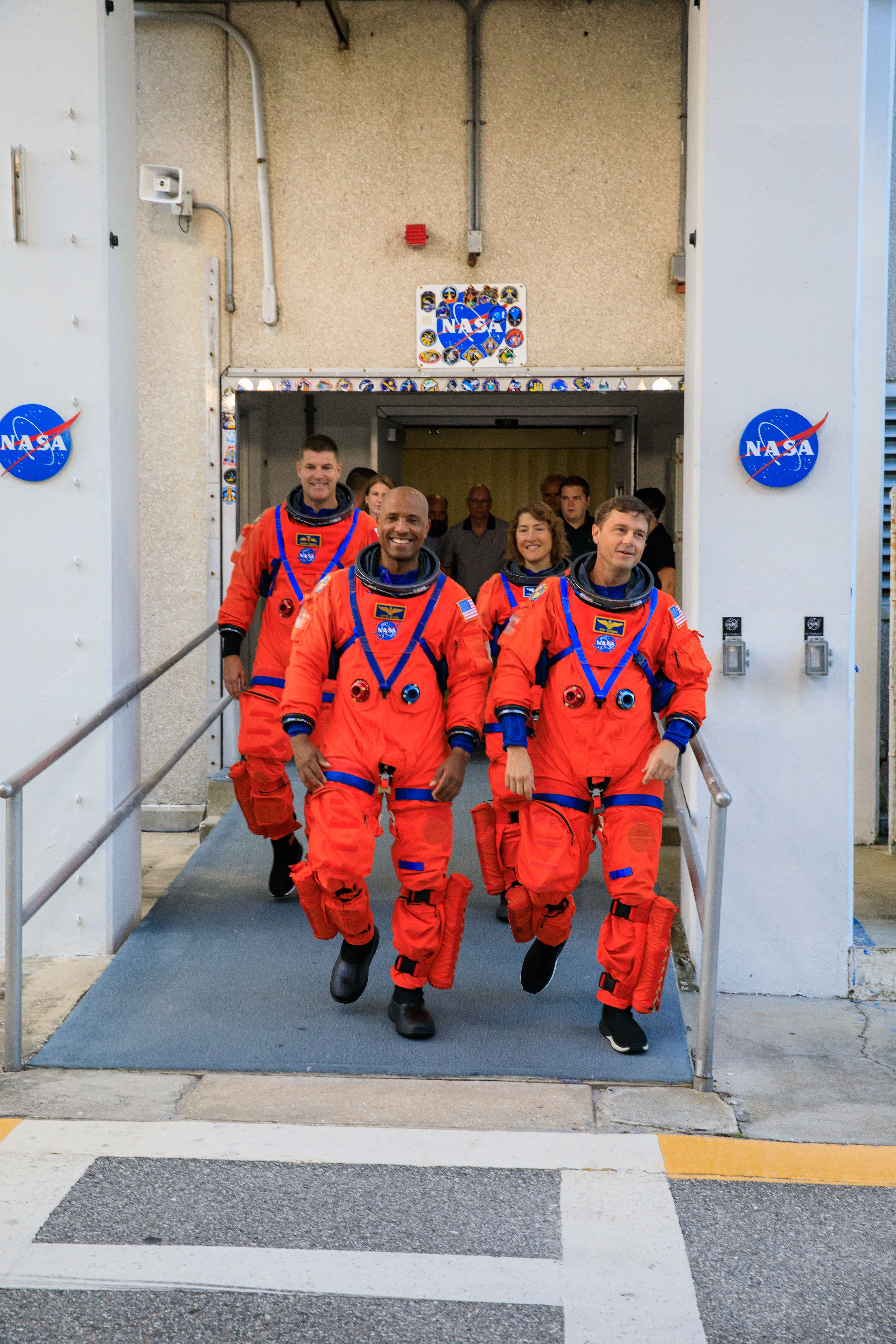 The four members of the Artemis II Crew walk out of a building.