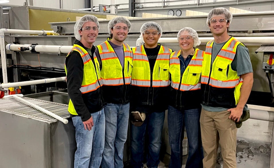 Marc Cabeliza poses with four other students, all in yellow safety vests and hairnets.