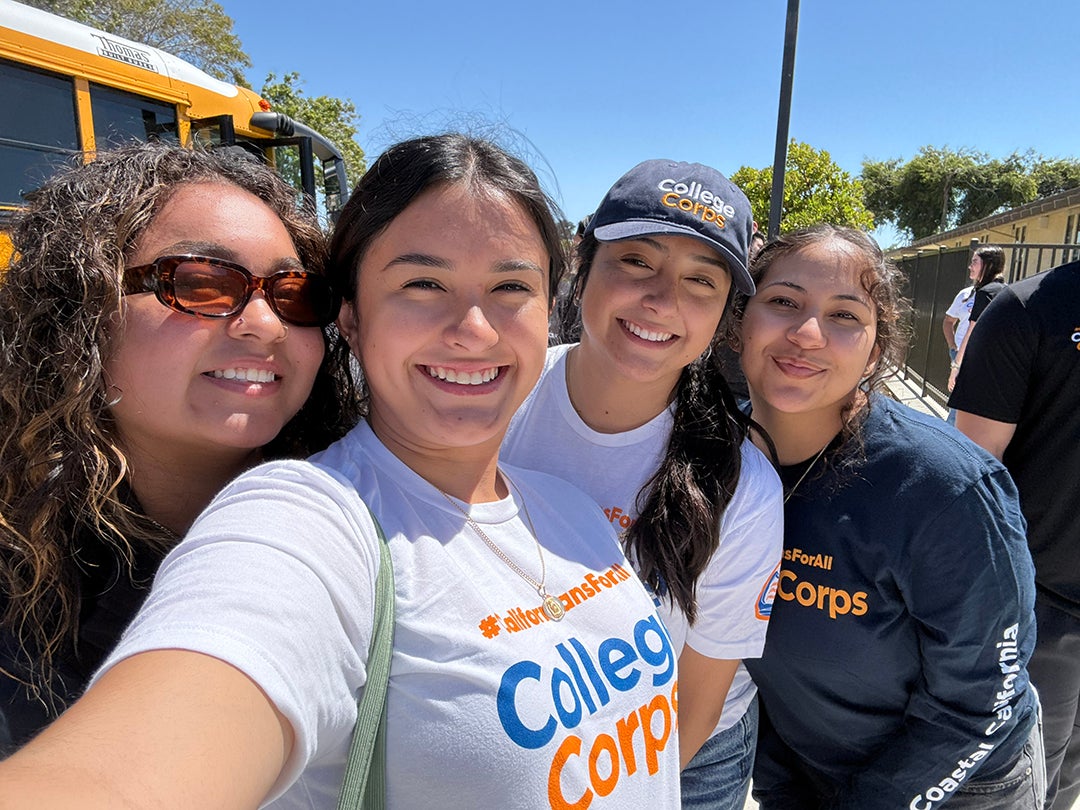 A group of four Cal Poly students smiles as they take a selfie.