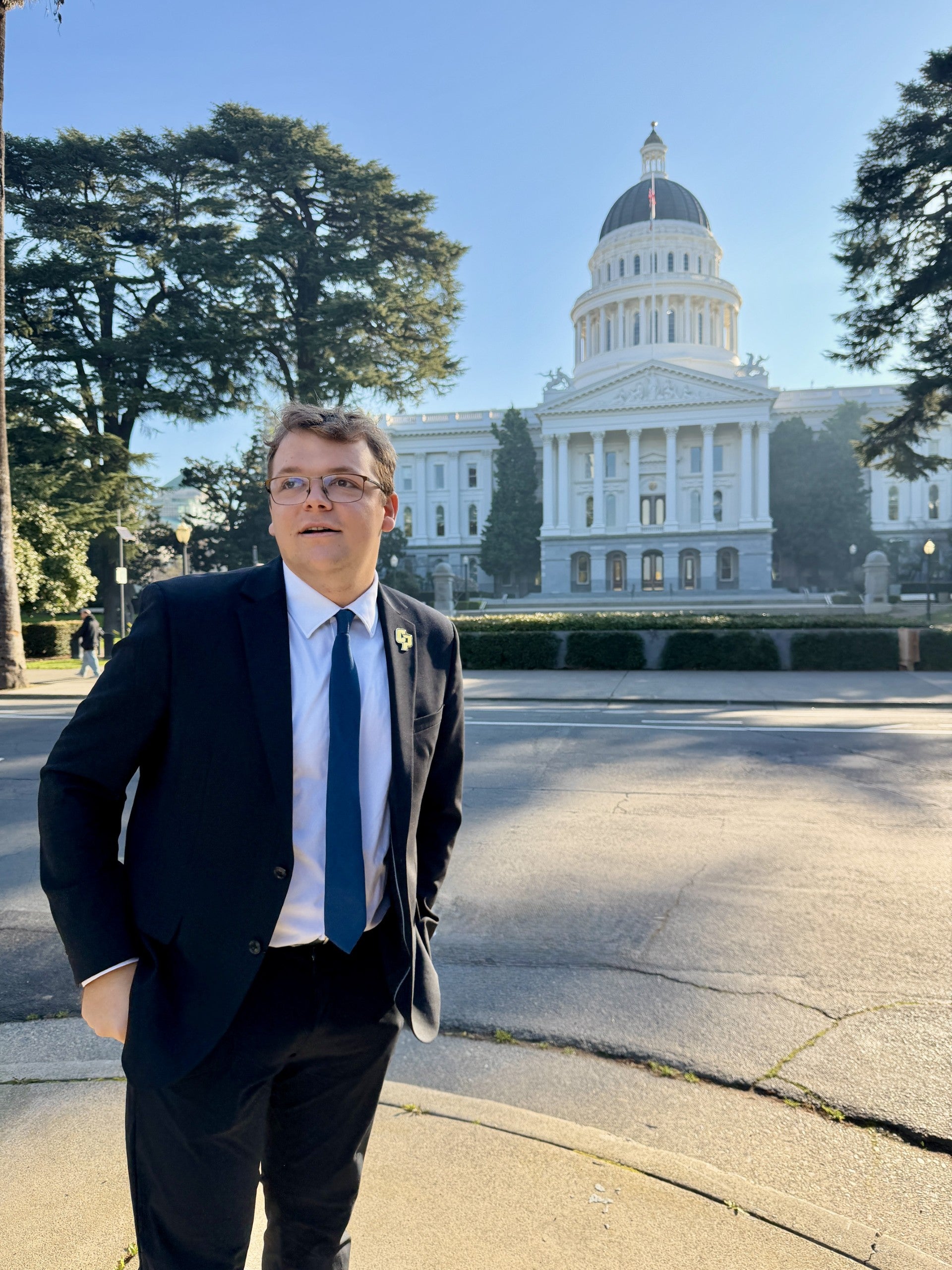 Julia, wearing a suit, poses outside a capitol building.