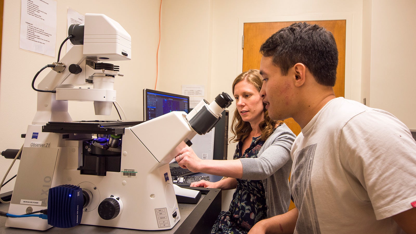 Professor helping student with microscope