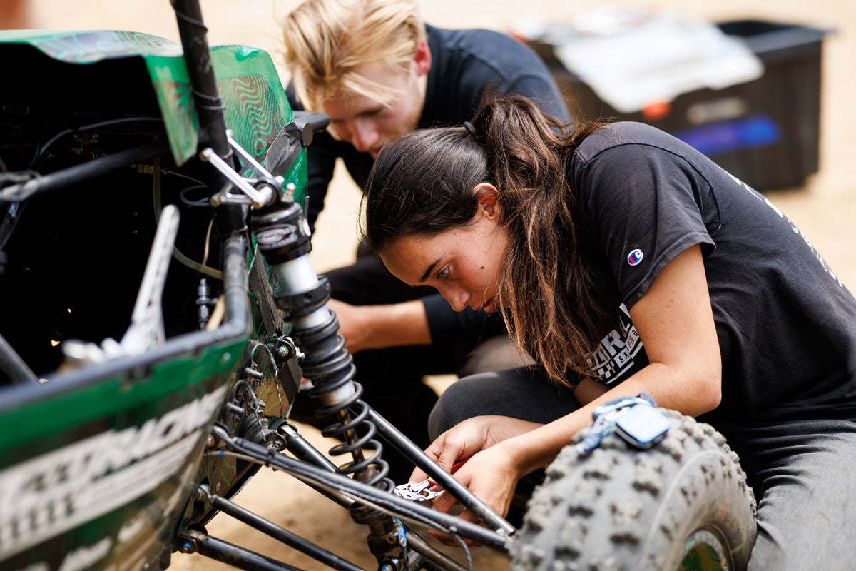 Two students fix the Cal Poly Racing Baja car during a testing day at a off-road course