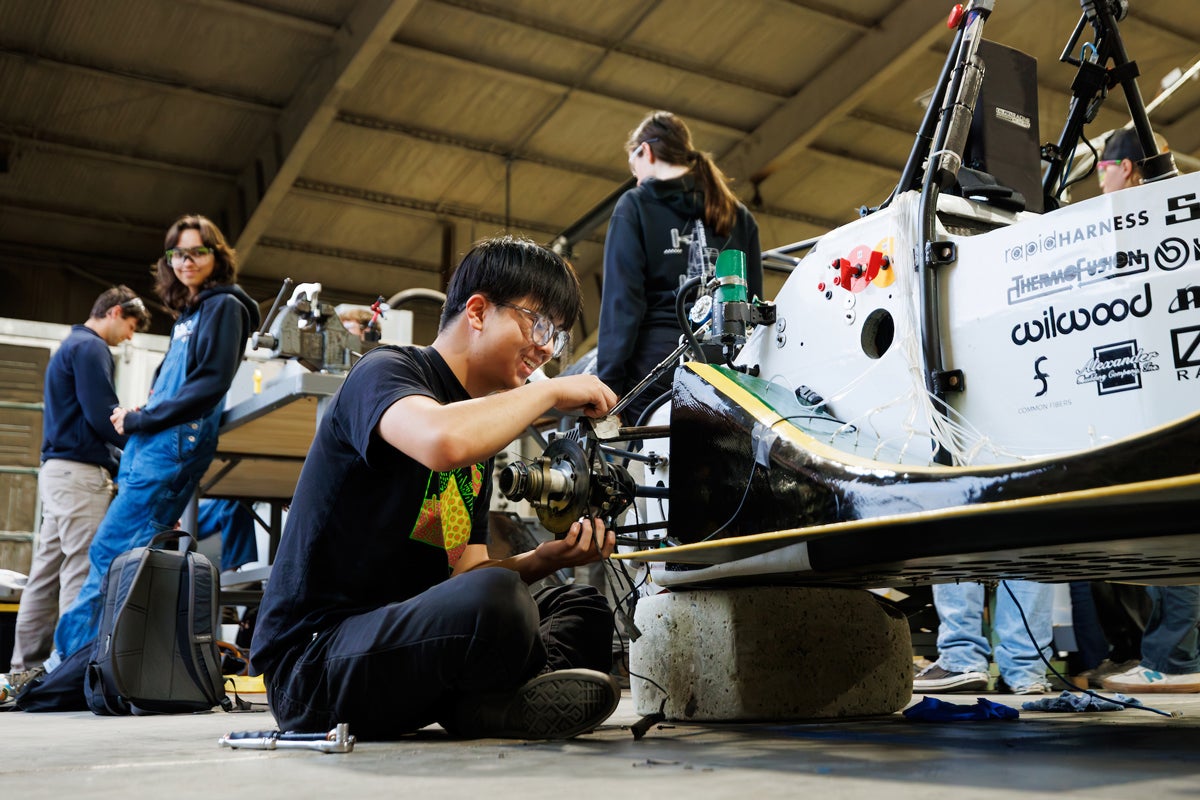 A student repairs the wheel of the Cal Poly Racing Baja car in the Aero Hangar during a work night