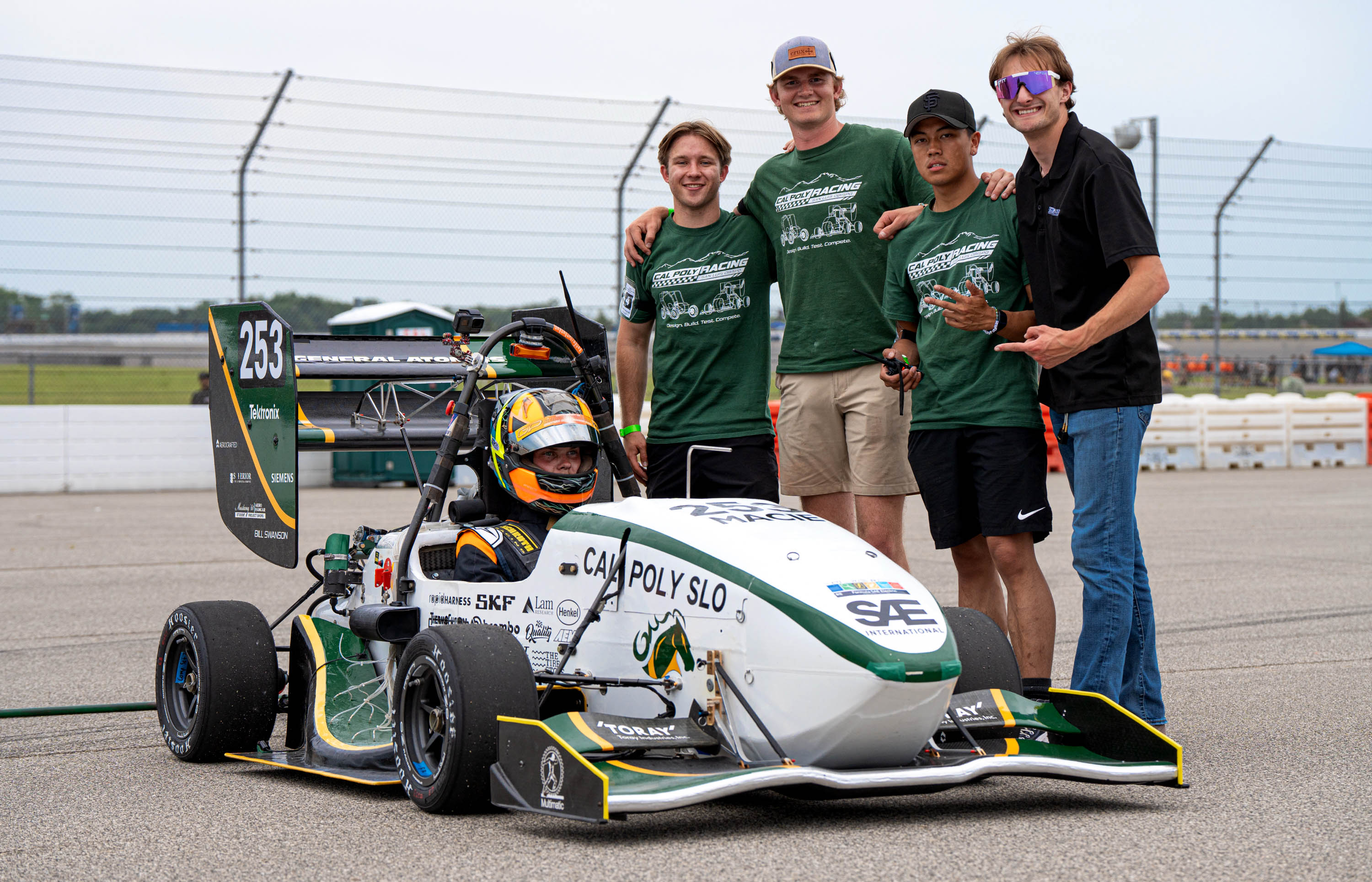 John O'Donnell poses with teammates and their race car on the track.