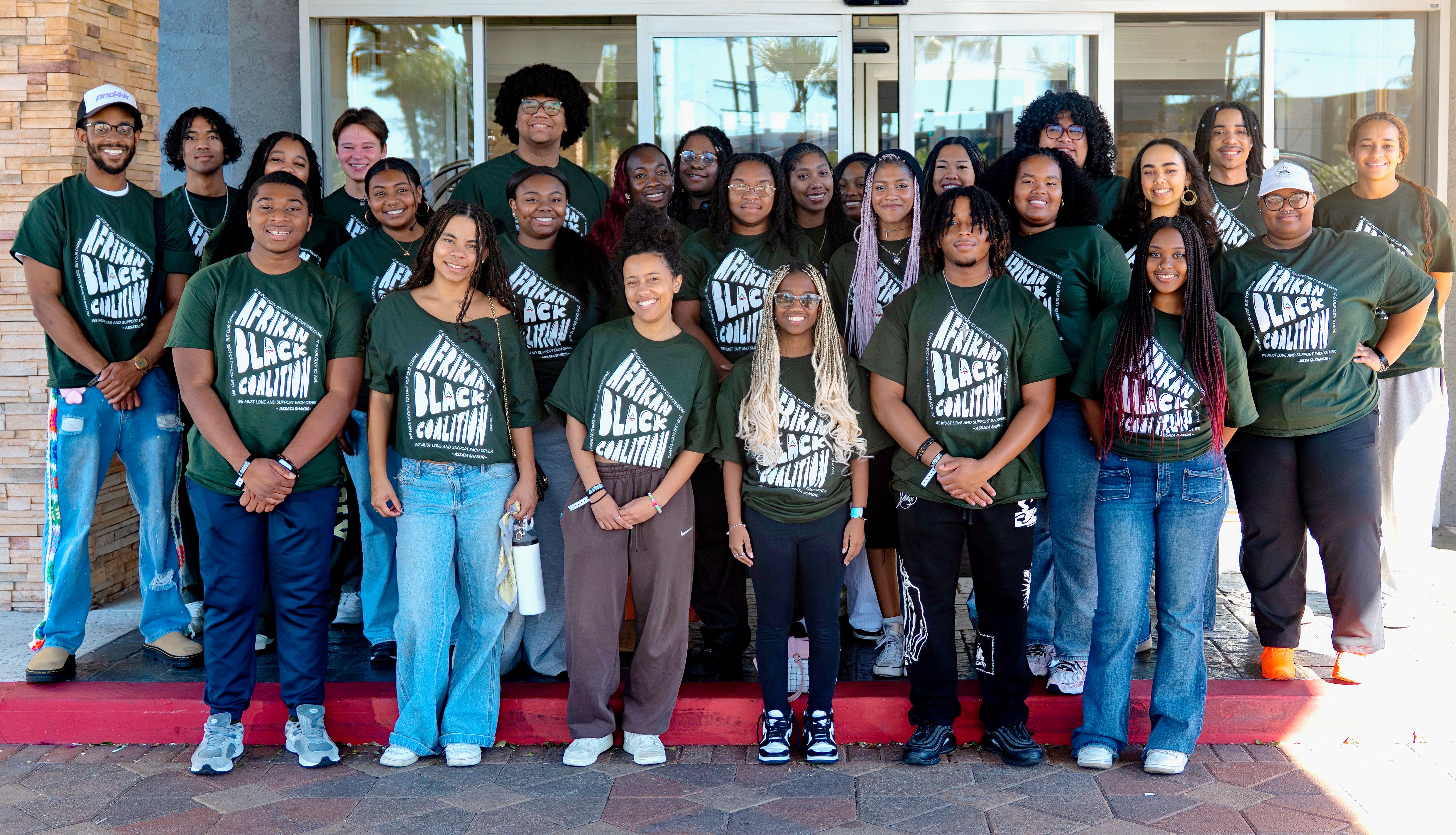 A group of students wearing green Afrikan Black Coalition shirts.
