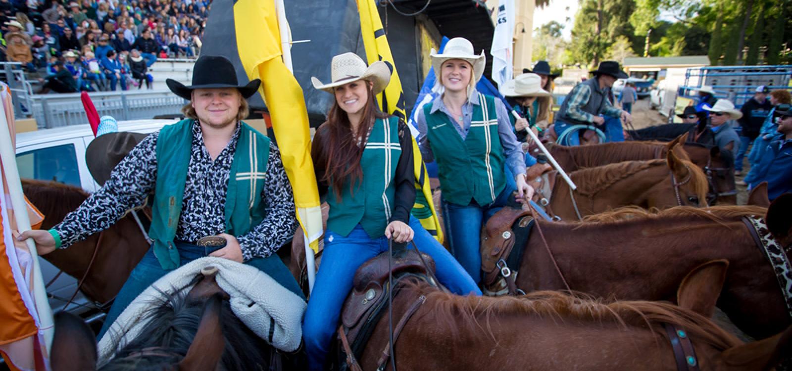 Cal Poly students smile for a photo on their horses at the 2018 Poly Royal Rodeo, held in Spanos Stadium.