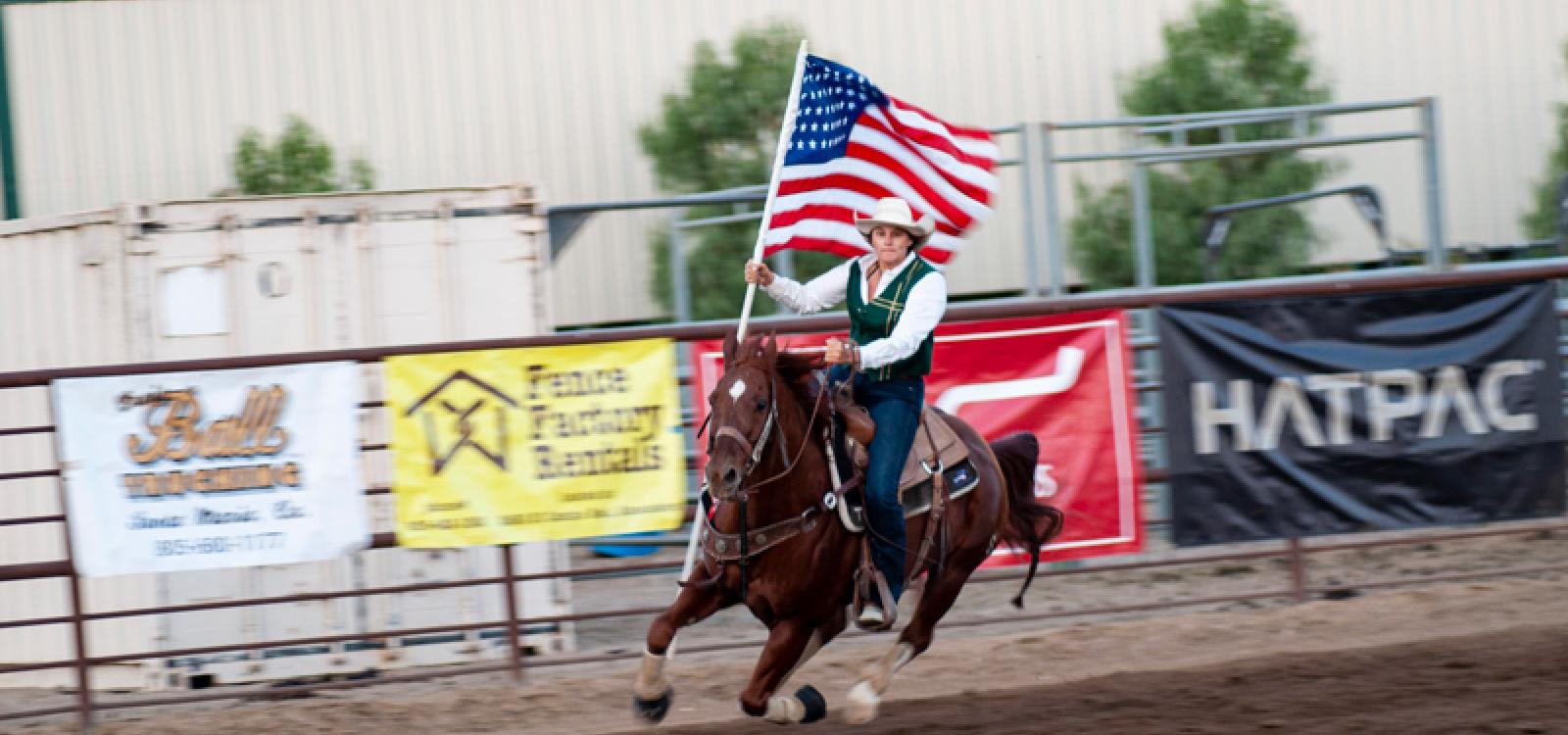 A student carries the American flag as she gallops around the ring in 2021.