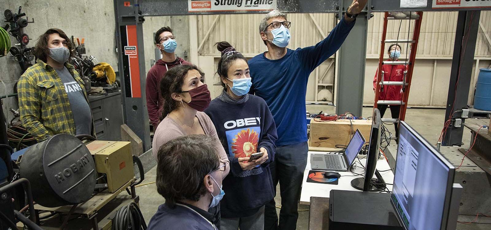 Professor Peter Laursen explains to students how to interpret sensor data to understand the plywood wall's behavior.