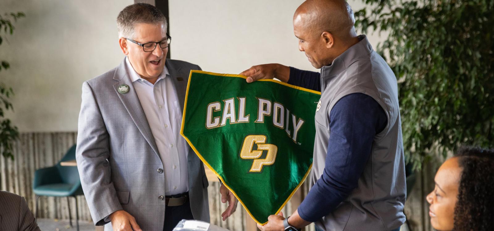 President Jeffrey D. Armstrong receives one of two Cal Poly banners that flew with Captain Victor Glover on the International Space Station
