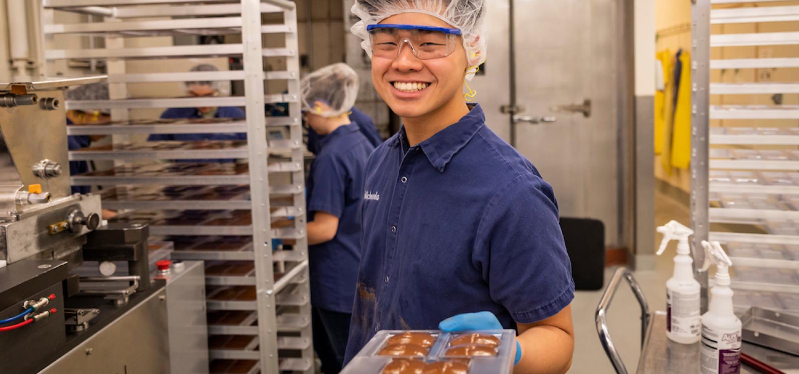 A student shows off a freshly-poured tray of Cal Poly chocolates.