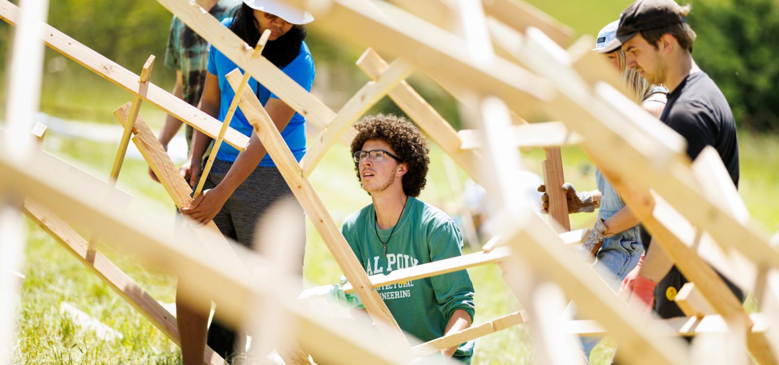 Students work on a wooden structure at Design Village. 