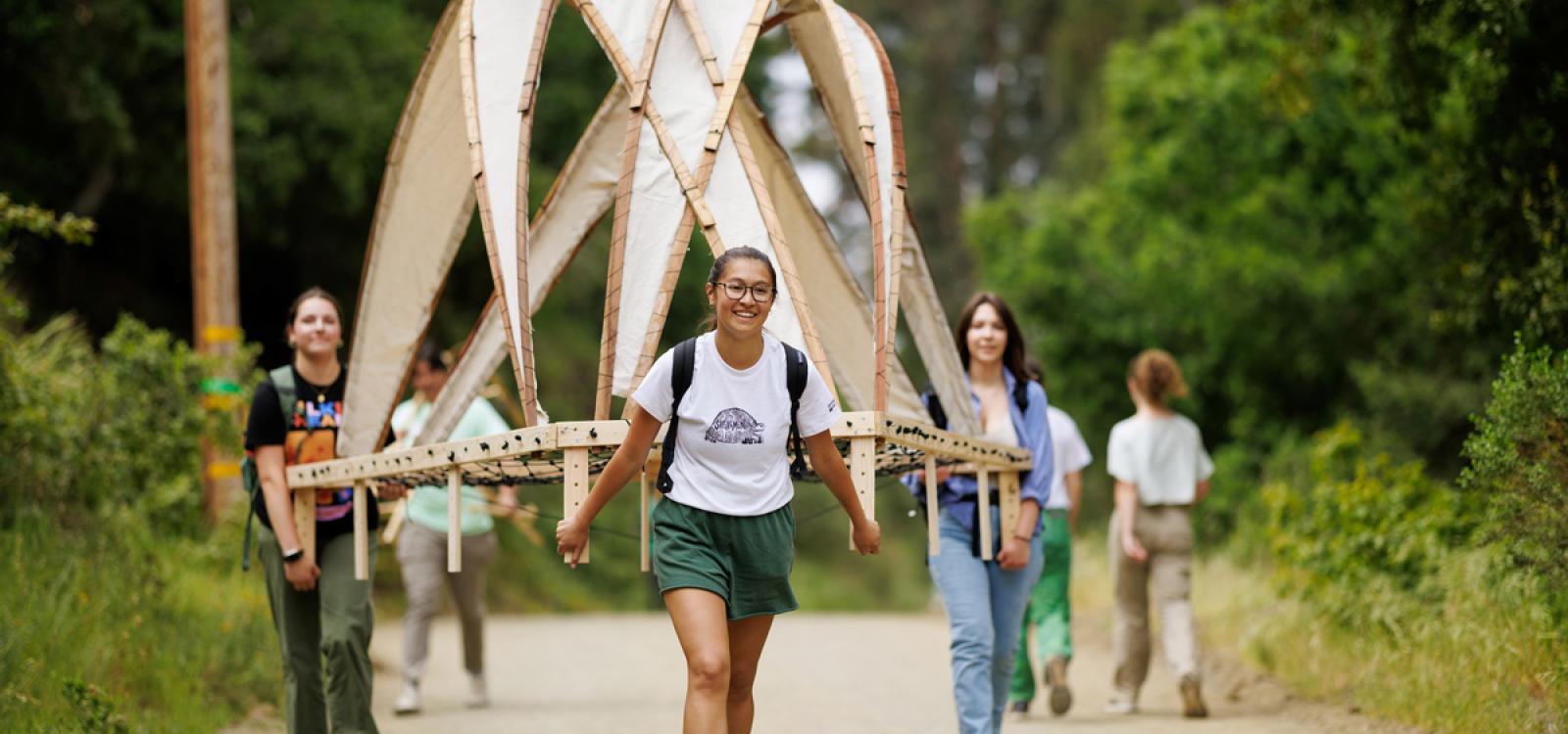 Students carry their designs on the mile-long trail to Poly Canyon.
