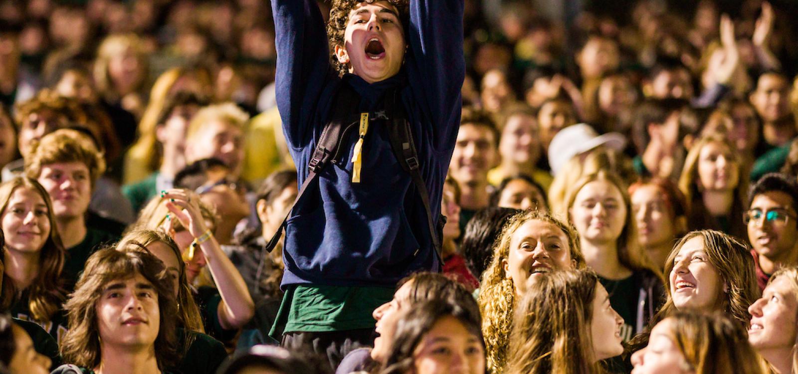 A student throws up their arms to cheer during the Big Fall Welcome on the first night of WOW.