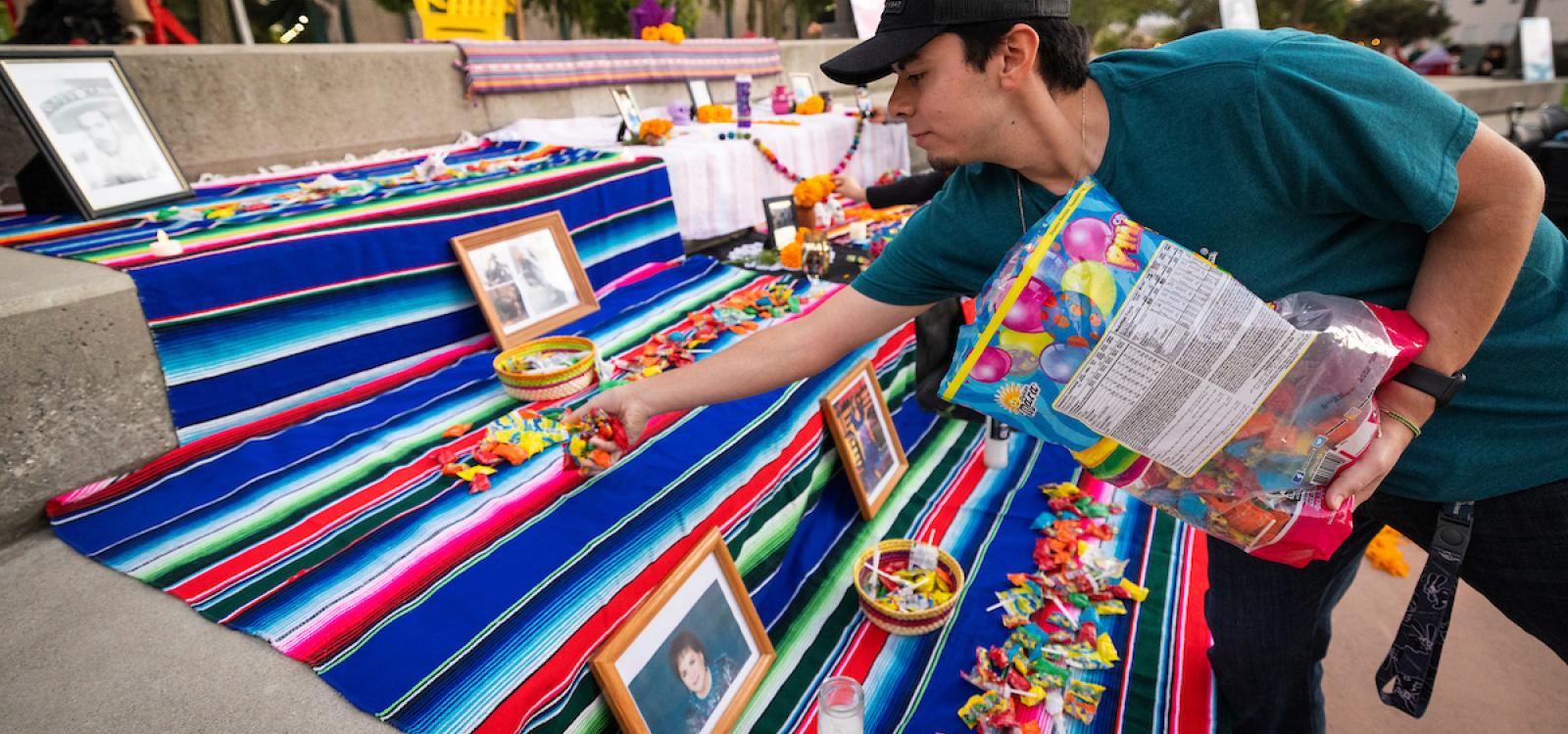 A student places candy on an ofrenda in the UU Plaza.