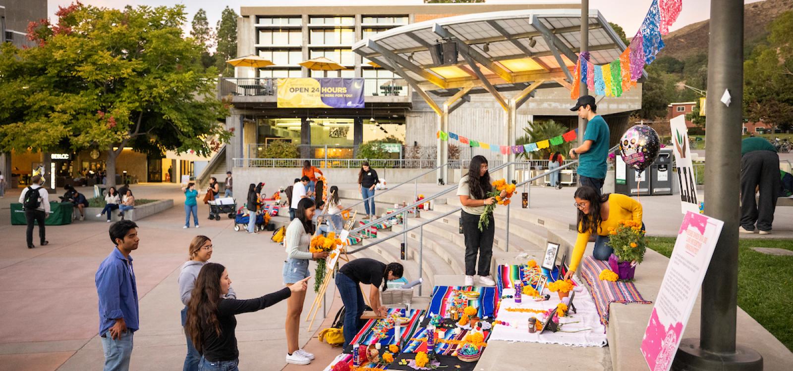 Students work together to set up ofrendas in UU Plaza as the sun sets during Día de los Muertos.