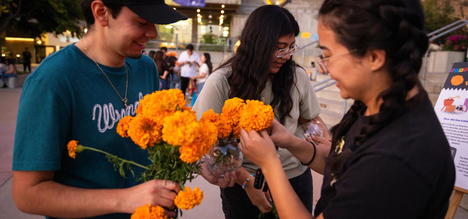 Students share smiles as they get marigolds to place on the ofrenda.