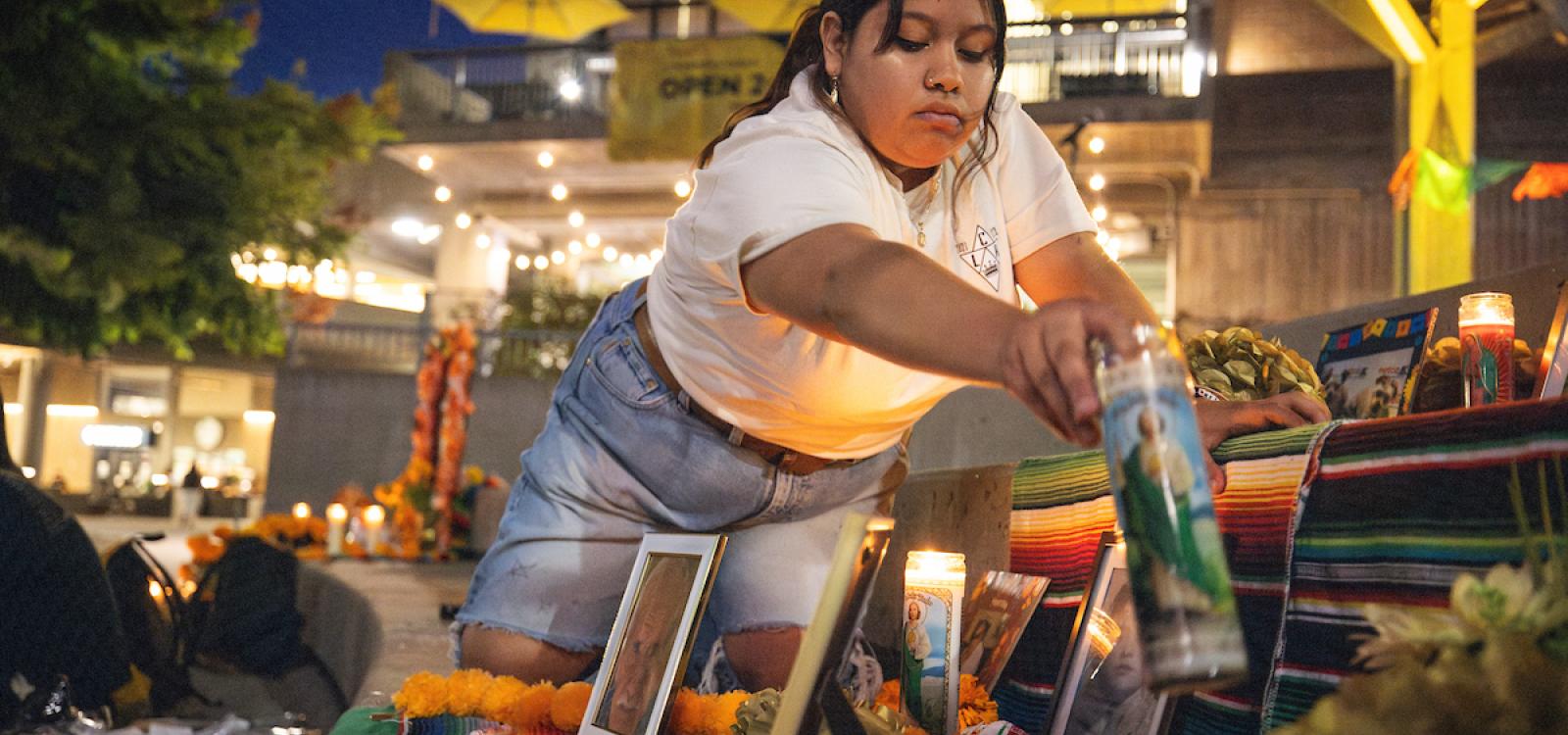 A student places a candle on an ofrenda, or altar, in UU Plaza. Campus community members set up the ofrenda as part of Día de los Muertos in early November.