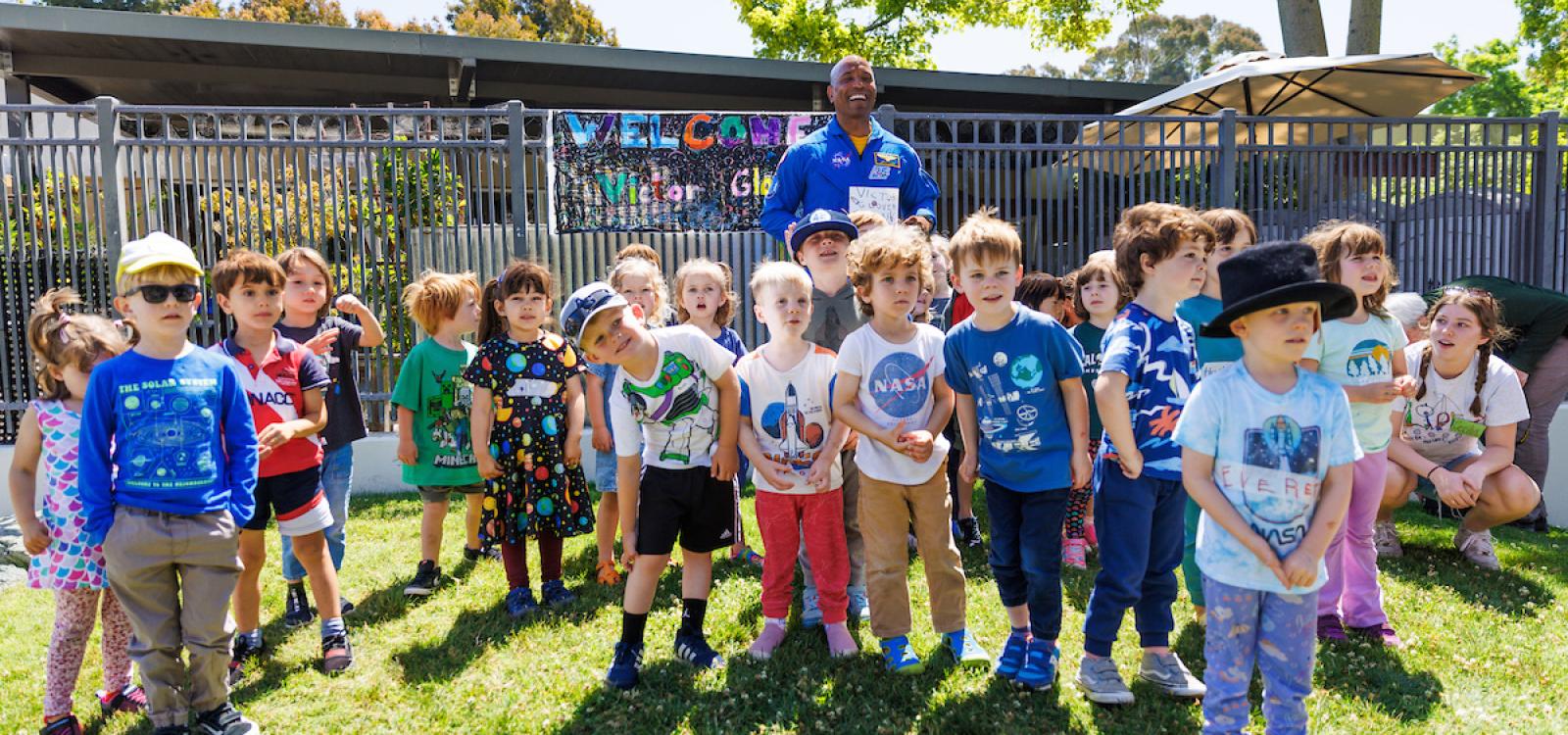Victor Glover poses for a photo with children at the Preschool Learning Lab. Many kids wore space-themed clothes for the visit.