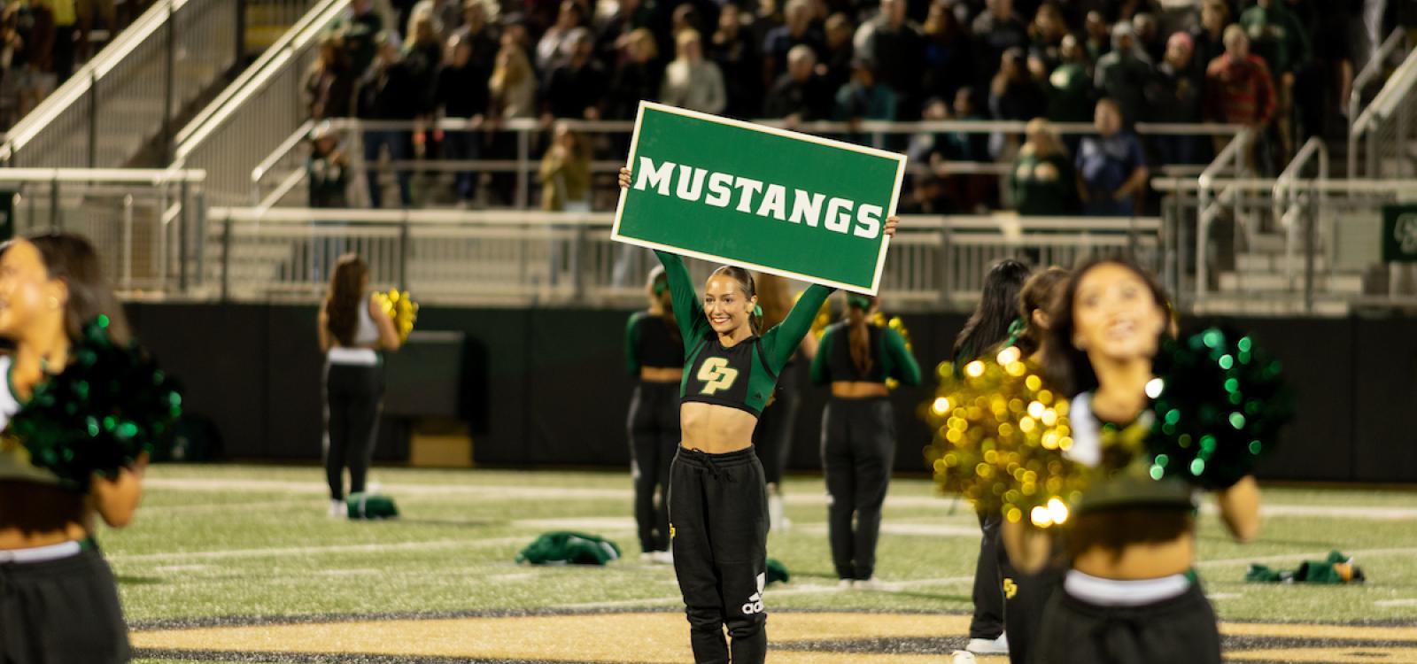 A cheerleader holds a Mustangs sign during Big Fall Welcome.