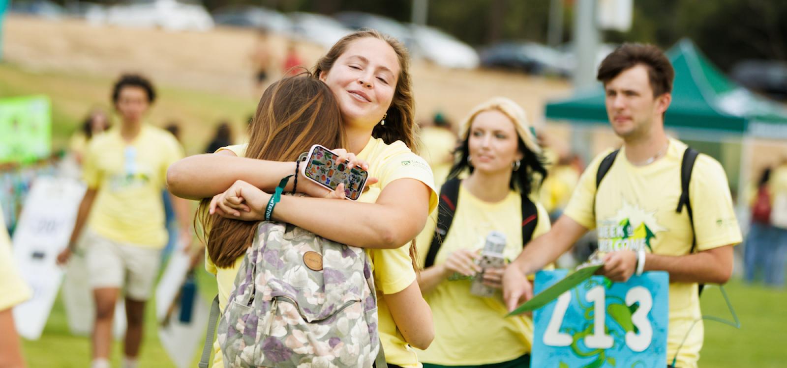 WOW leaders hug as they wait for new and transfer students at the WOW grouping.