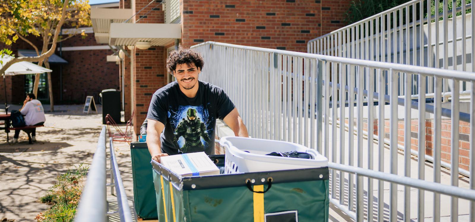 A student smiles as they push a cart during the Fall Mustang Move-In.