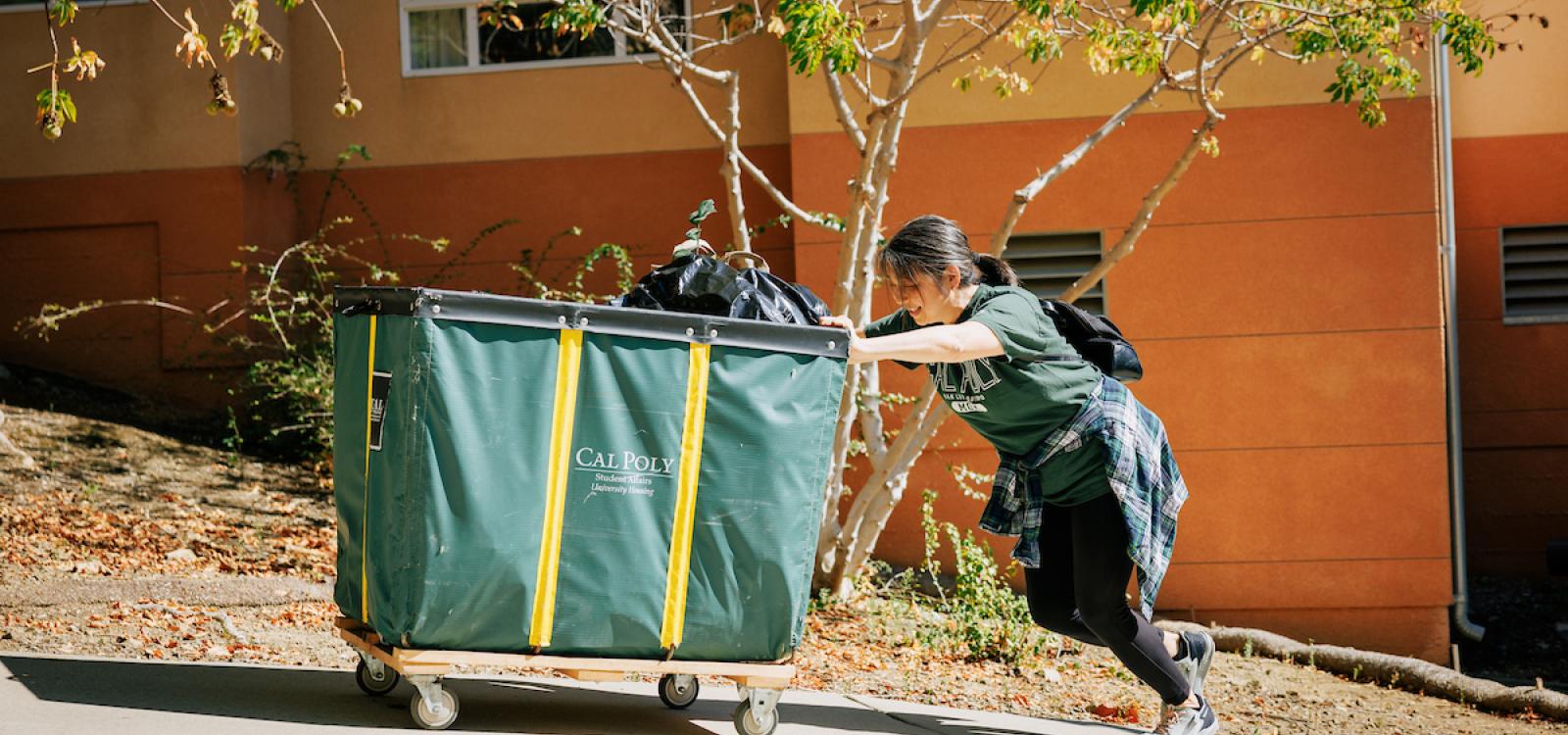A student pushes a cart full of belongings during the Fall Mustang Move-In.