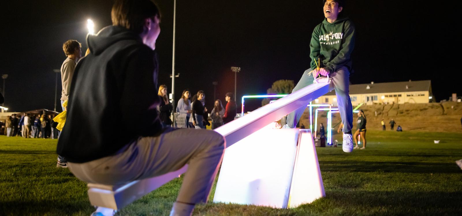 Students ride a seesaw at the WOW Carnival.