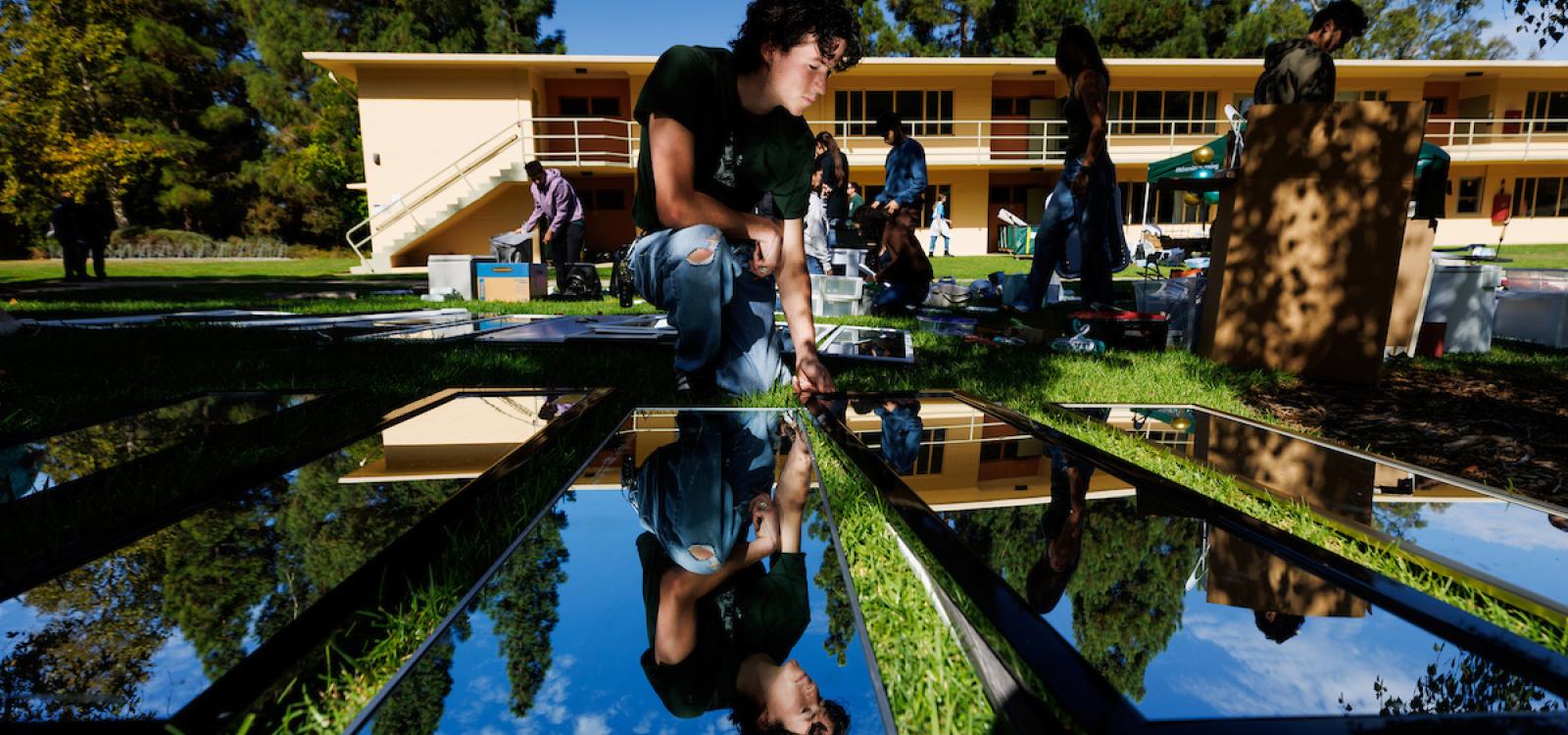A student looks at mirrors on a lawn near University Housing placed there by CP Thrift, an initiative to collect reusable items during move-out and make them available in the fall for Mustang Move-In. 