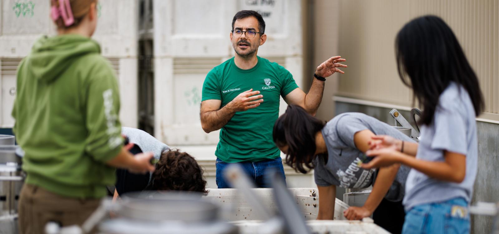 Enology professor Miguel Pedroza, center, speaks to students processing grapes.