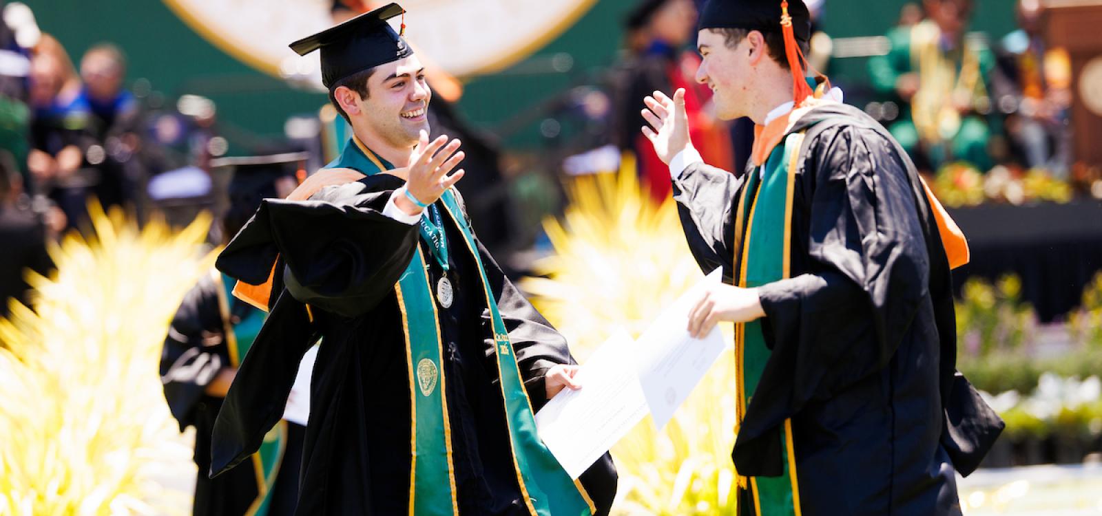Graduates high five at the College of Engineering commencement ceremony.