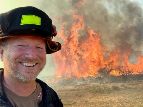 Photo of Chris Dicus with a fire in the background