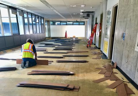 A construction worker works on flooring on the site of the Kennedy Library transformation.