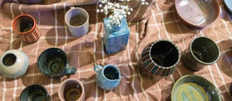 An overhead view of homemade mugs on a table.