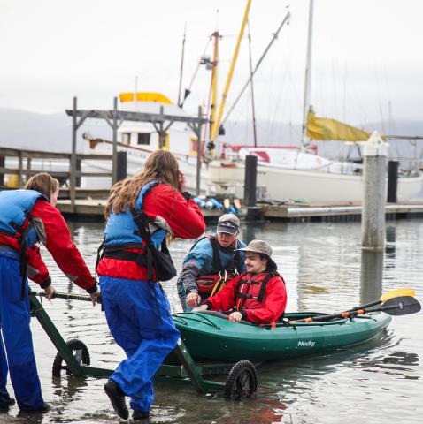 The Adapted Paddling Program support team helps a participant into the water in Morro Bay in 2019.