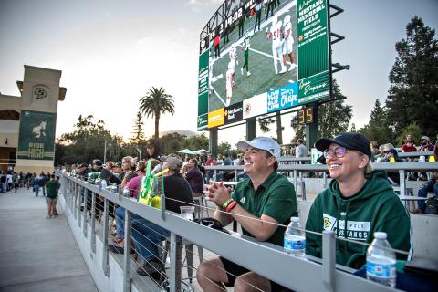 Spectators watching a football game at the Cal Poly Partners Plaza.