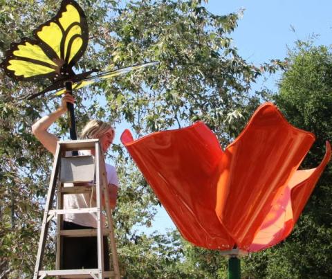 Madeline Xiong, Aiden Largay and Irene Han lift and position the hand-bent steel petals of their poppy sculpture during installation in the Children’s Garden.