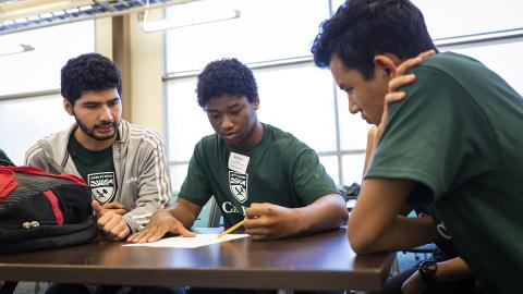 Young students look at a paper together.