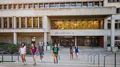 Students walking out of Kennedy Library at sunset.