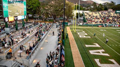 People watching a football game in Cal Poly Partners Plaza.