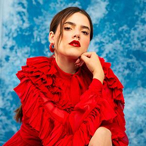 A headshot of Camila Fernández wearing a red close and earrings.
