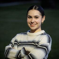 A headshot of Olivia Huyler in a striped sweater.