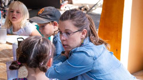 An ASI staff member talking with small children.