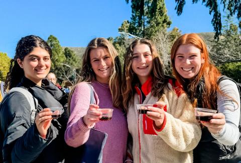 A group of students hold their beverages up to the camera