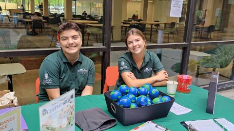 Two students sitting at an event booth for International Education Week.