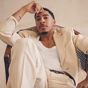 Pianist and composer Christian Sands sitting on a chair.
