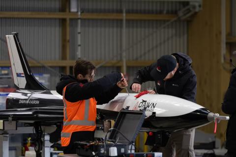 Students work on a spaceplane in a hangar.