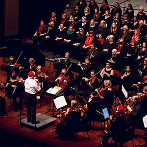 The SLO Master Chorale performing on stage with an orchestra.