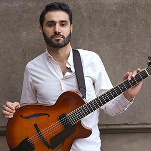 A photo of Adam Moezinia holding a guitar.